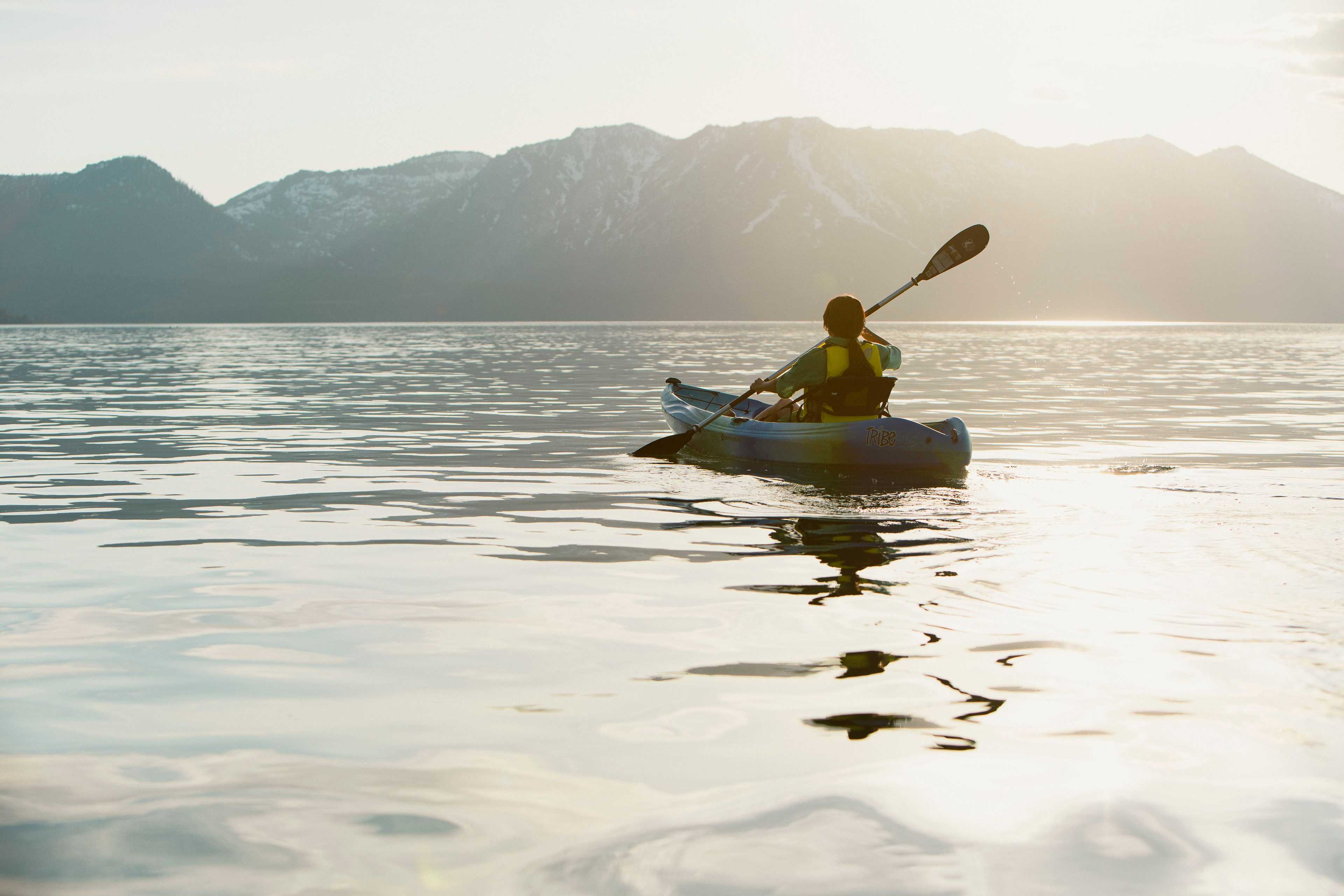 kayaker paddling into the sunset on Lake Tahoe with mountains in the background image